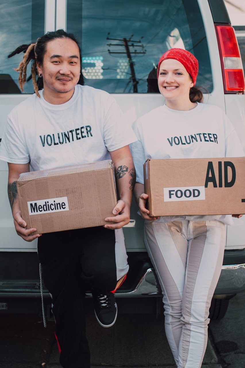 Free Two volunteers holding aid boxes with medicine and food labels, supporting charity causes. Stock Photo